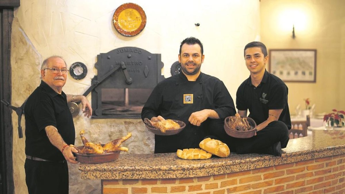 Rubén García junto a su tío Pedro García y su hijo Sergio, a la puerta del horno de asar de leña en el comedor del restaurante.-
