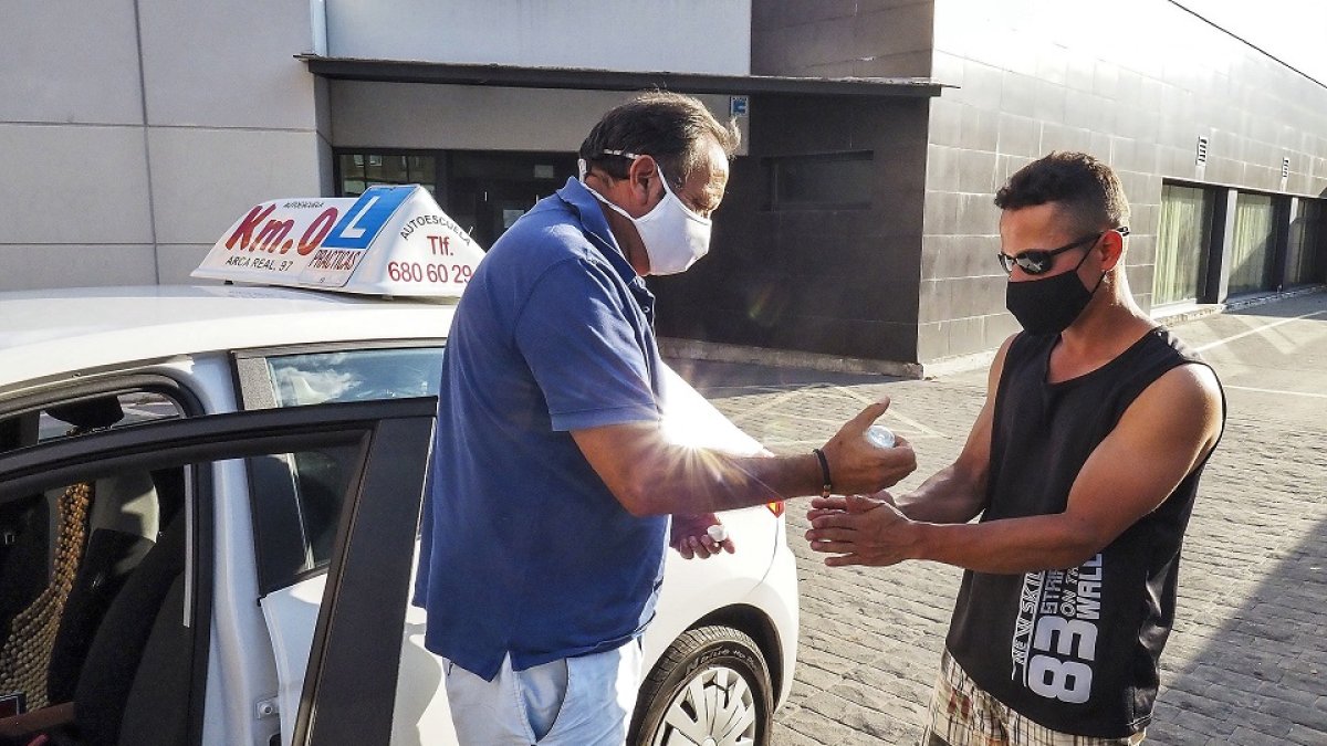 El profesor de la autoescuela Km.0, en Valladolid, ofrece gel hidroalcohólico al alumno antes de comenzar una práctica con el coche. PHOTOGENIC/MIGUEL ÁNGEL SANTOS