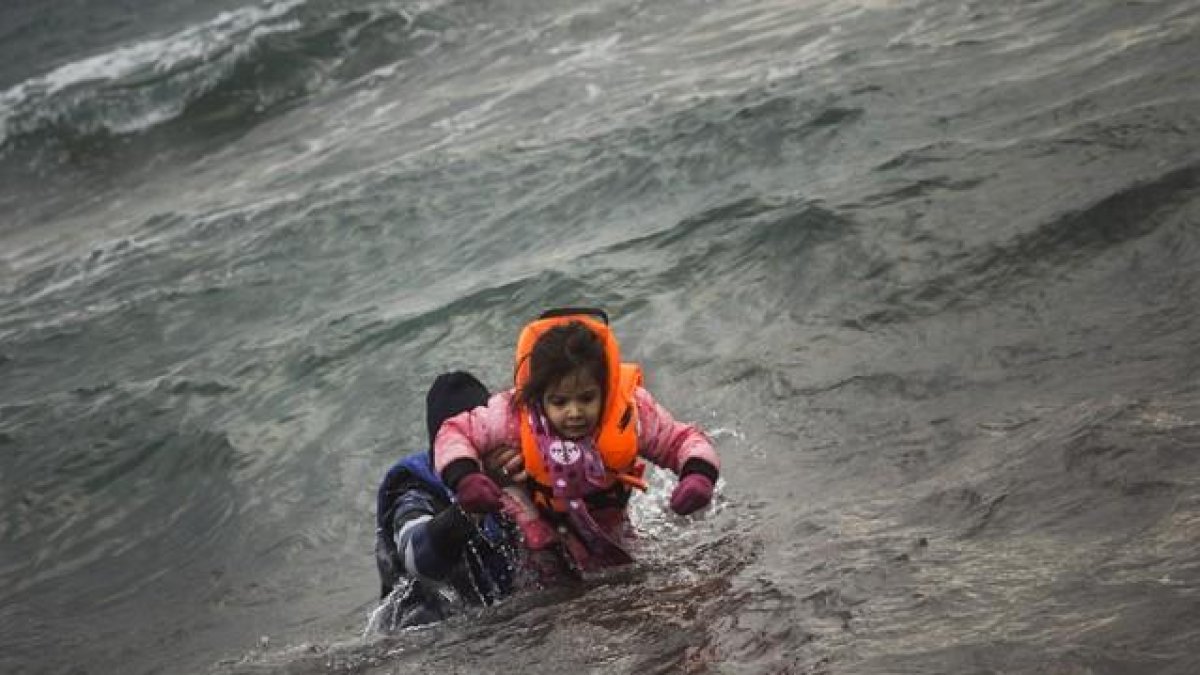 Un hombre ayuda a un niño cuyo barco ha naufragado este domingo en el Egeo.-AFP / Santi Palacios / AP