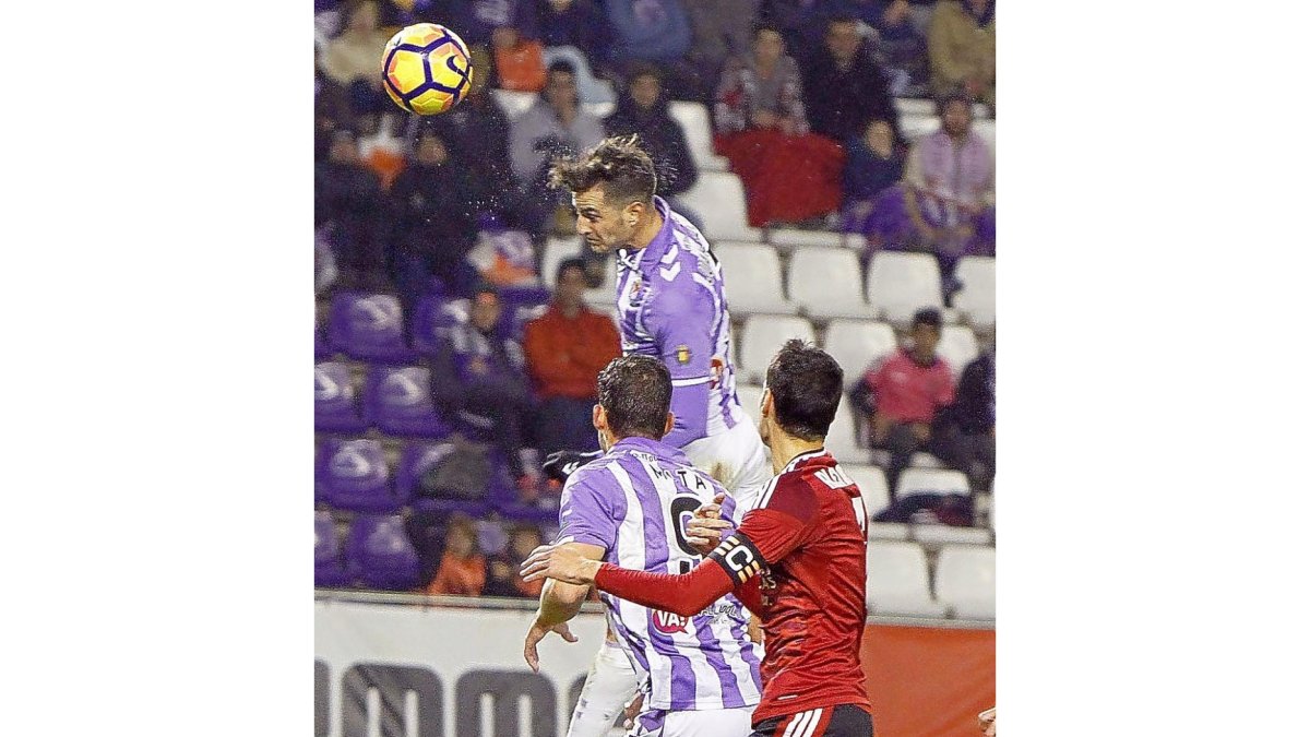 Juan Villar cabecea para marcar gol ante el Mirandés, ante Jaime Mata y Álex Ortiz.-J.M. LOSTAU