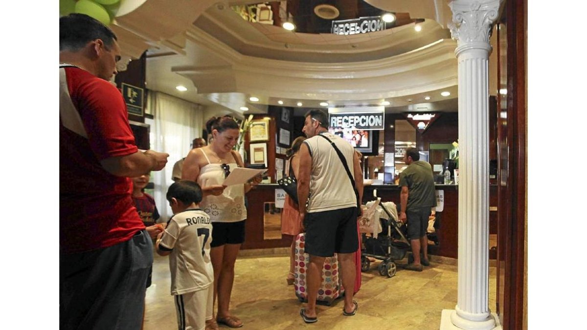 Turistas en la recepción de un hotel.-EL MUNDO