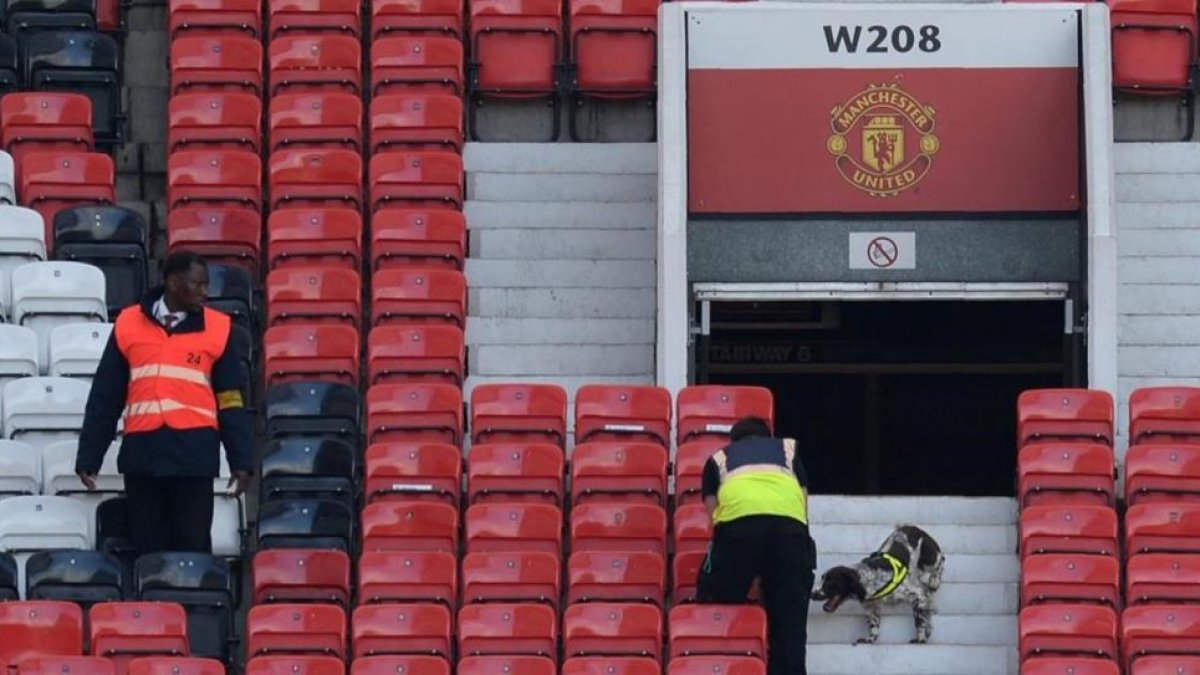 Miembros de seguridad rastrean las gradas de Old Trafford.-AFP / OLI SCARFF