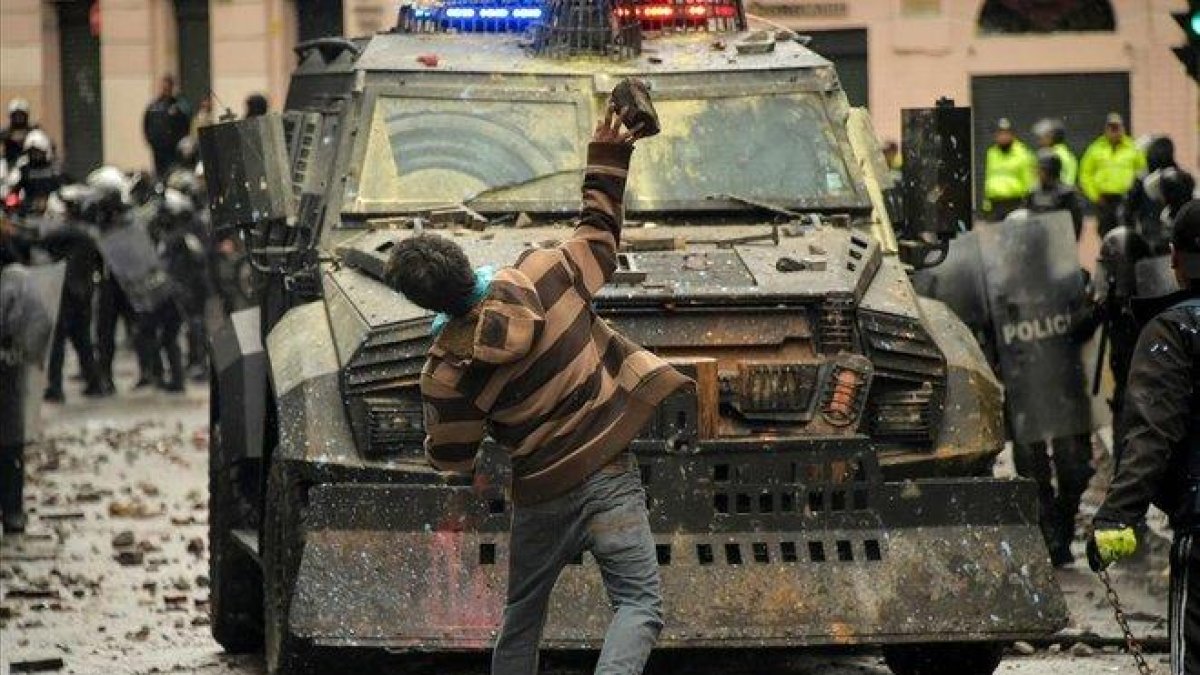 Un manifestante lanza un objeto contra un vehículo policial en una protesta contra el Gobierno de Lenin Moreno, este viernes, en Quito.-RODRIGO BUENDÍA (AFP)