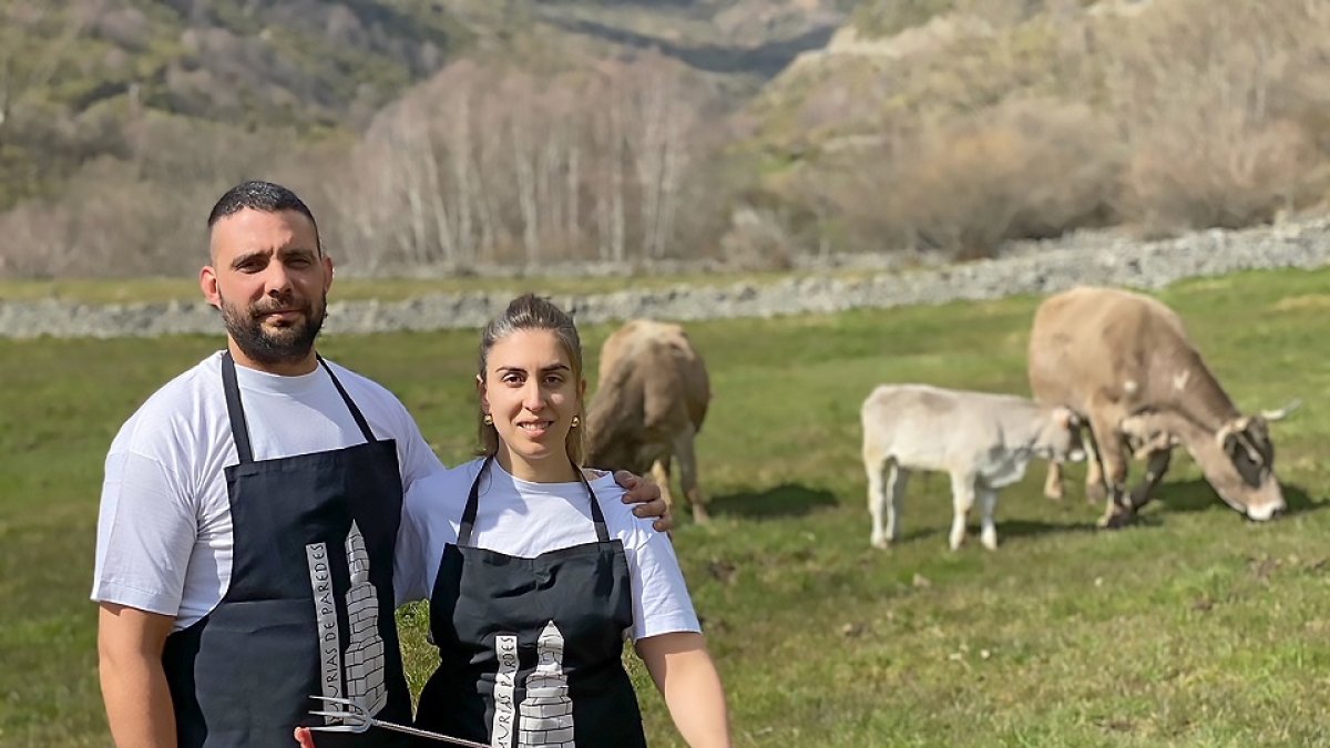 Aída y David frente a terneras de raza parda de su explotación con algunas de las piezas de carne que comercializan online y sirven en su restaurante. / E.M.