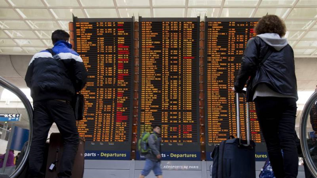 Dos viajeros comprueban la información de los vuelos en las pantallas del aeropuerto Charles de Gaulle, en Roissy (Francia).-Foto: EFE