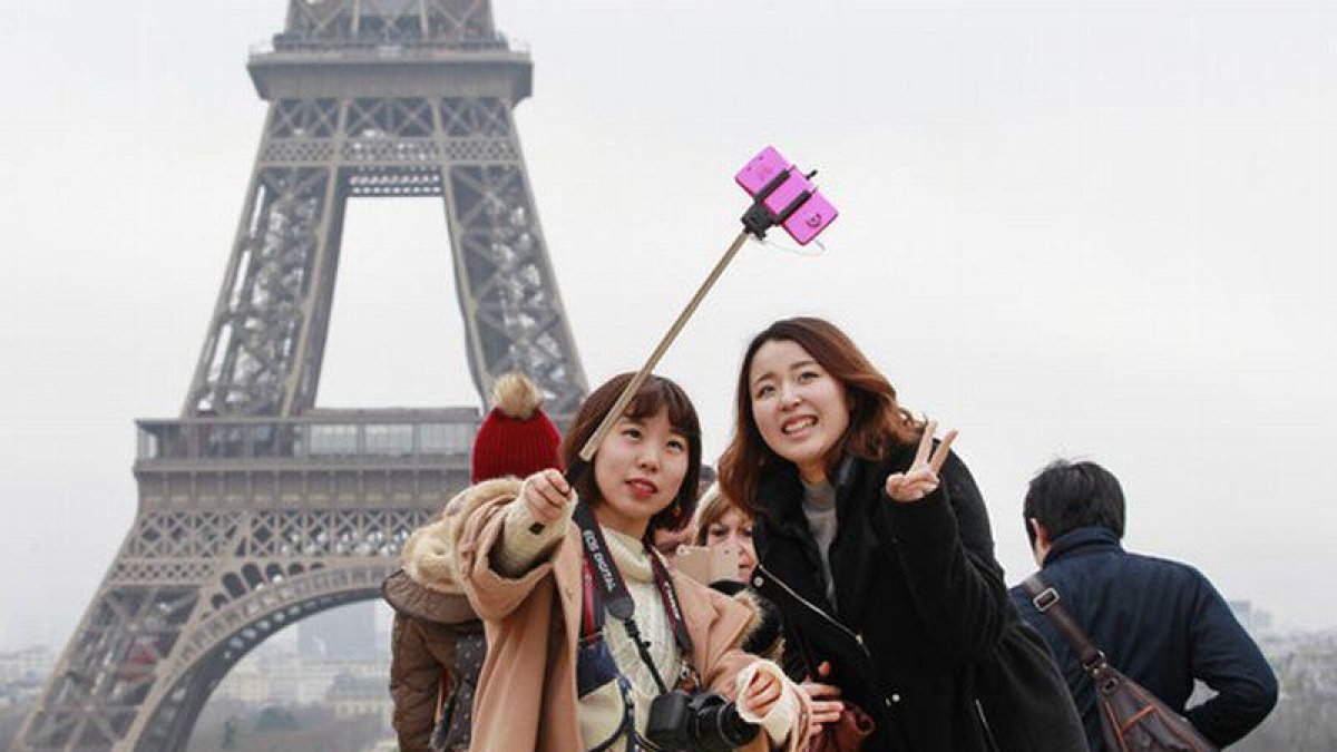 Turistas utilizando del palo para hacerse selfis en París.-