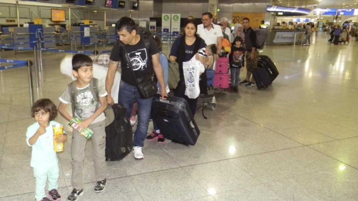 Los primeros refugiados procedentes de Grecia de origen sirio e iraquí acogidos en España, en la cola de facturación en el aeropuerto de Atenas, antes de partir hacia Madrid, el 24 de mayo del 2016.-EFE / YANNIS CHRYSSOVERGHIS