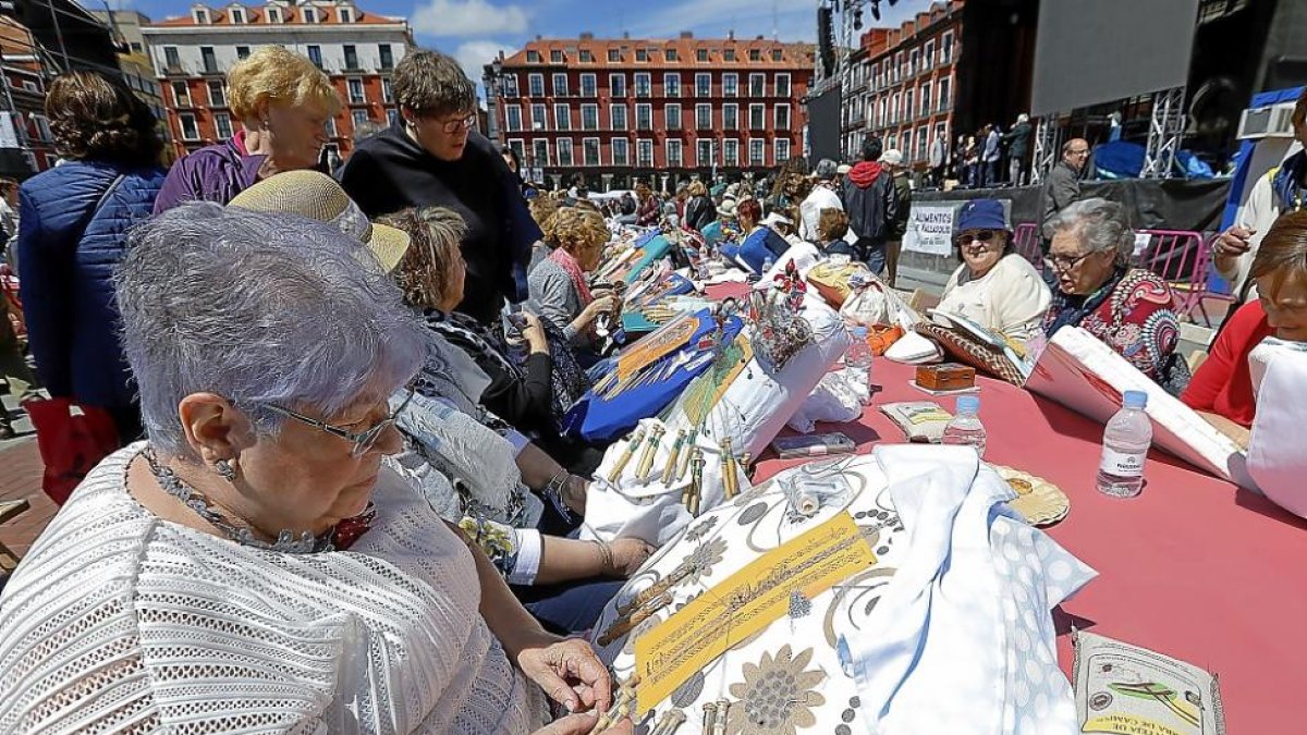 Varias mujeres entretejen sus encajes de bolillos, ayer en la Plaza Mayor durante el II encuentro celebrado con motivo de las fiestas patronales.-J.M. LOSTAU