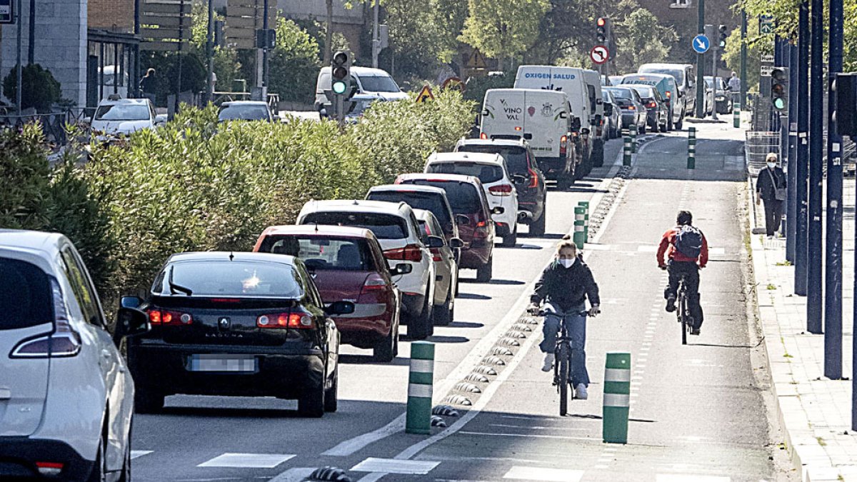 Usuarios del carril bici en la Avenida Isabel la Católica junto a una hilera de vehículos impulsados por motores de explosión a base de hidrocarburos. PHOTOGENIC