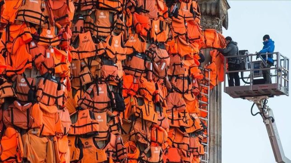Asistentes del artista Ai Weiwei colocan chalecos salvavidas en la Kinzerthaus de Berlín, en recuerdo de los refugiados.-AFP / JOHN MACDOUGALL