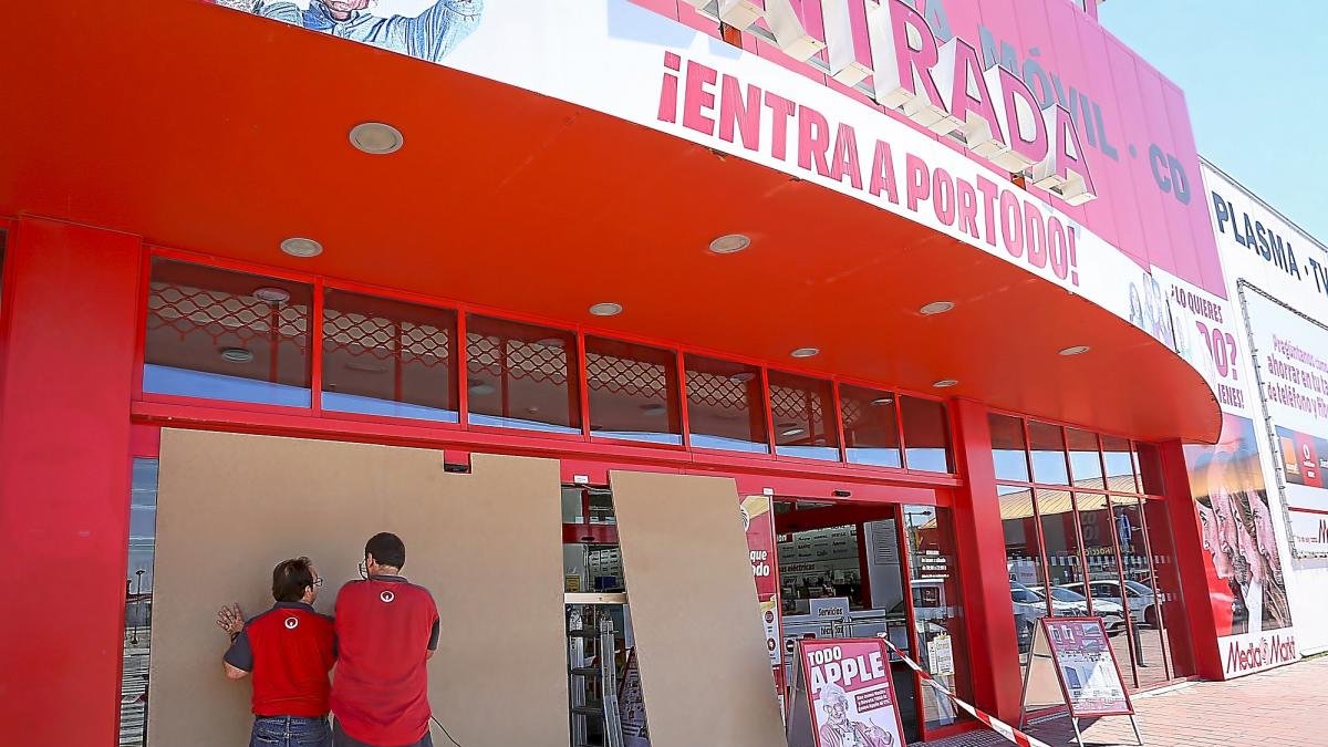Operarios colocan paneles en la puerta de Media Markt que los ladrones extrajeron de cuajo con cuerdas.-J.M. LOSTAU