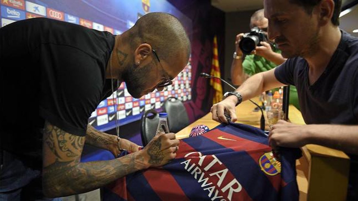 Dani Alves firma una camiseta antes de su comparecencia.-Foto: AFP / LLUÍS GENÉ