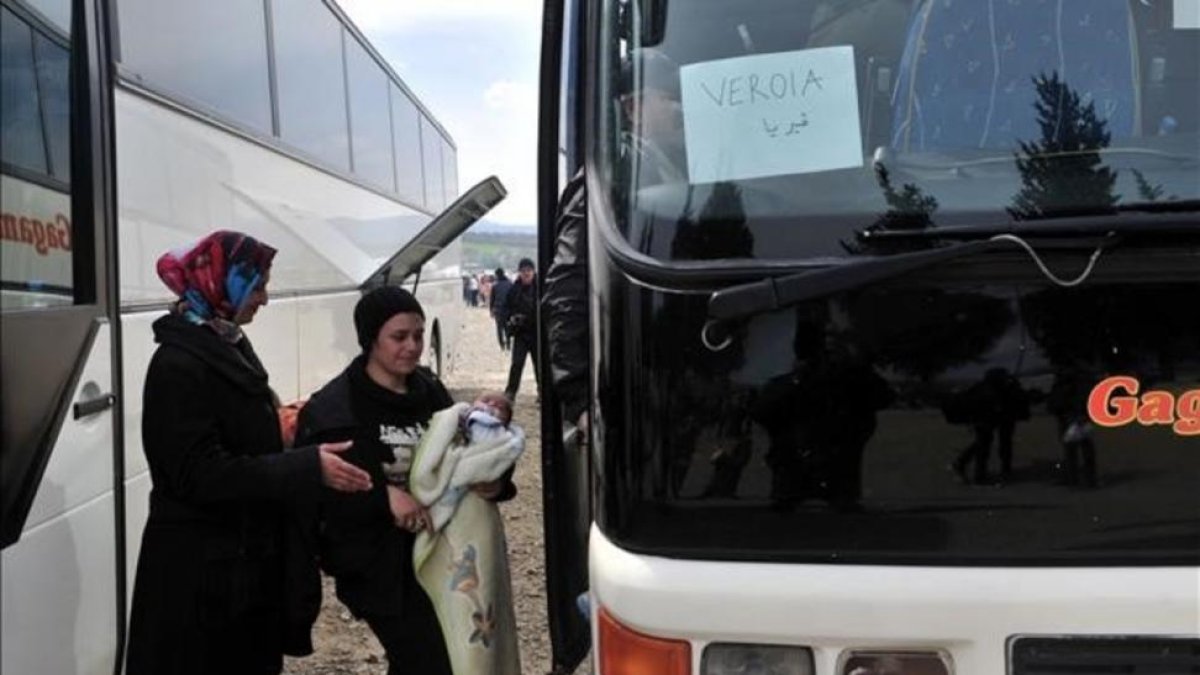 Dos mujeres se disponen a subir a un autocar en el campamento de Idomeni.-AFP / SAKIS MITROLIDIS