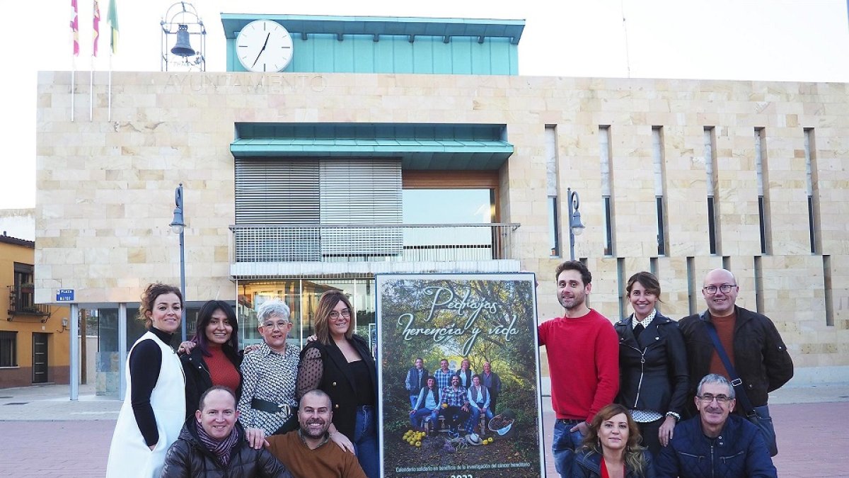 El equipo de organización del calendario posa junto al cartel de presentación en la Plaza Mayor de Pedrajas. EUROPA PRESS