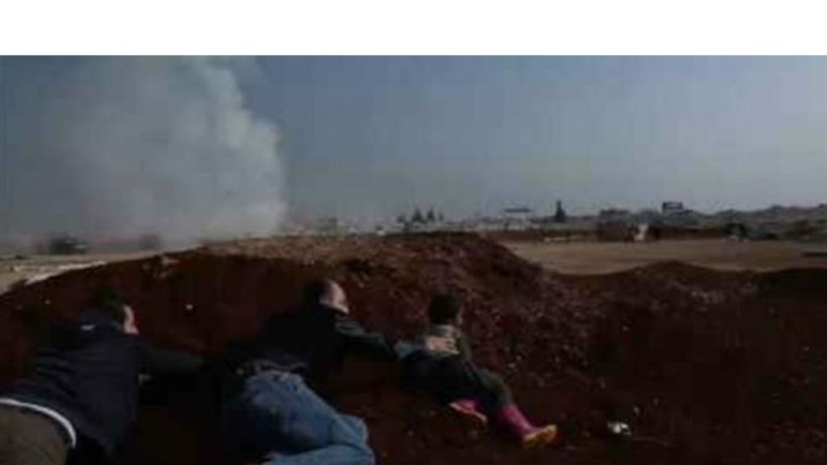 Un niño y dos adultos se esconden tras el ataque con misil contra el campo de desplazados en la provincia de Idleb.-/ PERIODICO
