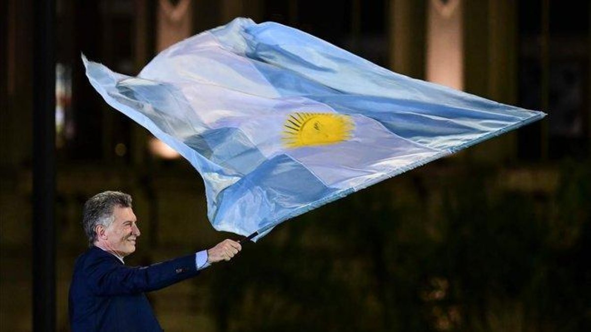 Macri ondea una bandera argentina en el mitin de clausura de su campaña electoral, en Córdoba.-AFP / RONALDO SCHEMIDT