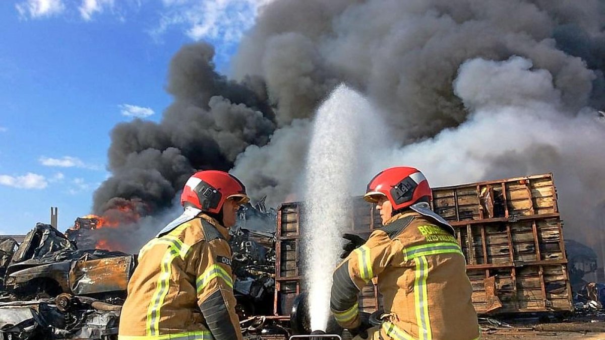 Imagen de archivo de dos bomberos junto a un camión incendiado en Valladolid. / E.M.