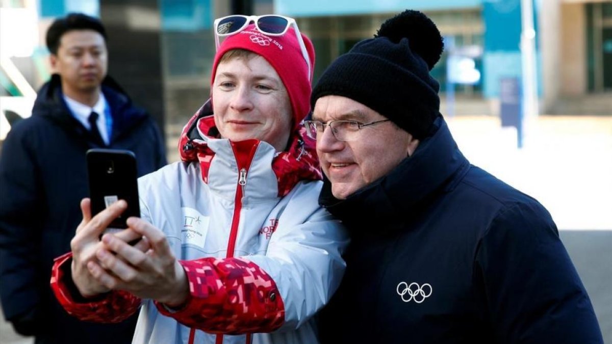 El presidente del COI, Thomas Bach, se hace un selfi con una voluntaria en Pieonchang.-EFE