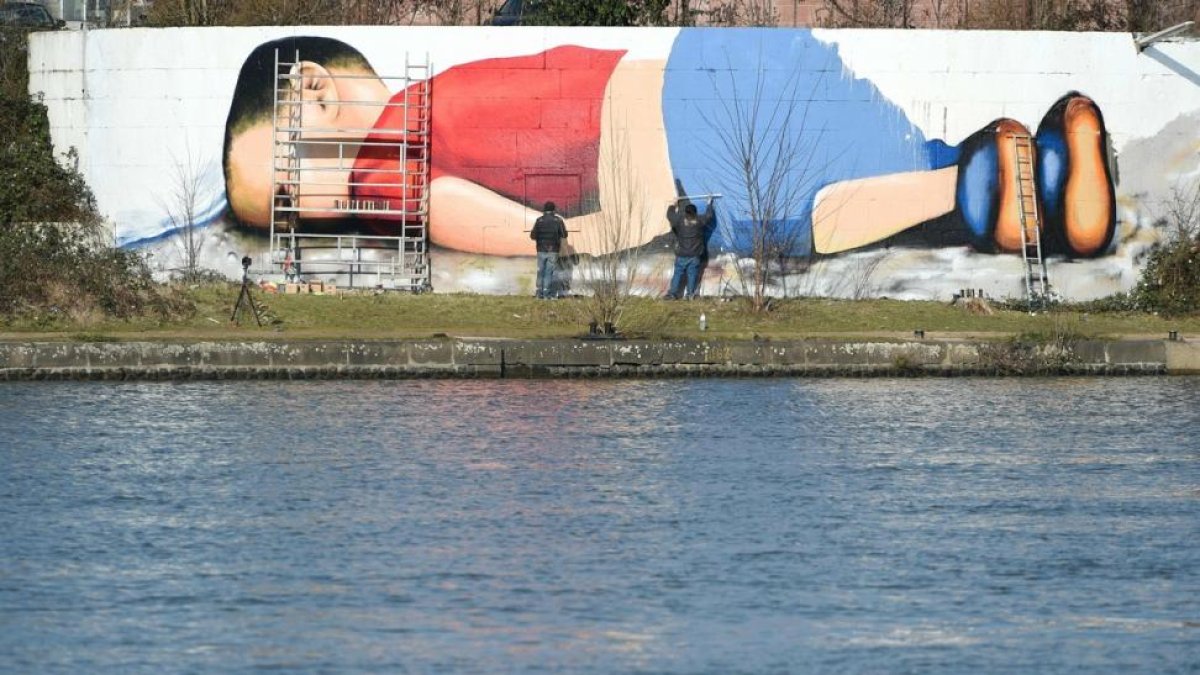 Enorme grafiti de Aylán en la orilla del río que cruza Fráncfort.-AFP / ARNE DEDERT