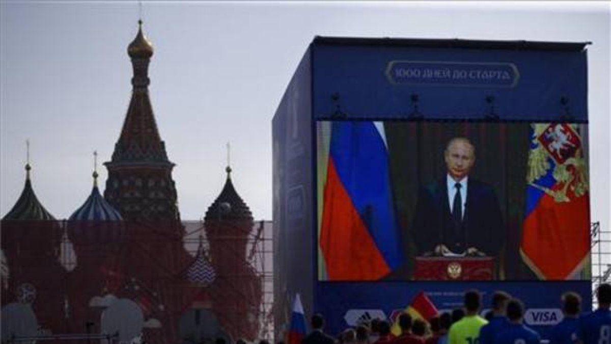 Un grupo de funcionarios y jugadores de fútbol miran el discurso televisado del presidente ruso, Vladimir Putin, en la Plaza Roja de Moscú, este viernes.-AP