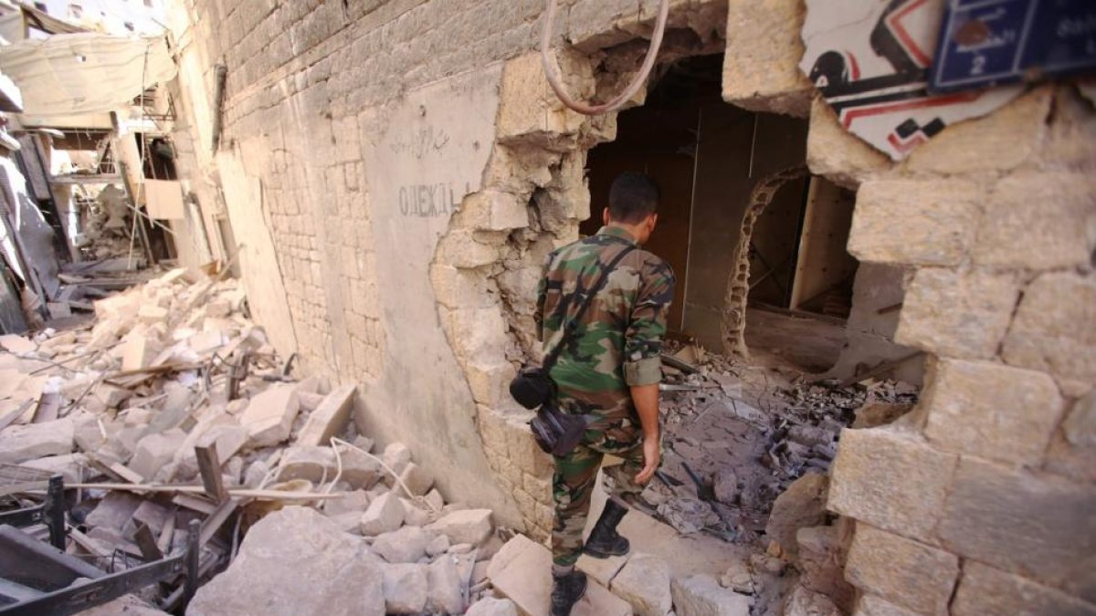 Un soldado del Ejército sirio inspecciona un edificio dañado en Alepo.-AFP / YOUSSEF KARWASHAN
