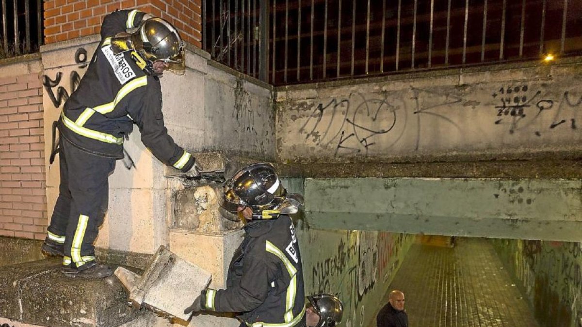 Los bomberos recogen las losas que se desprendieron de la pared del paso subterráneo.-Miguel Ángel Santos