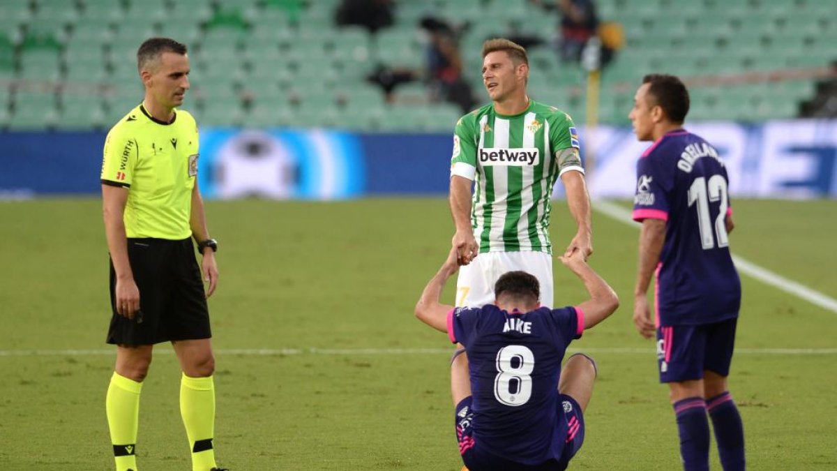 Real Betis' Spanish midfielder Joaquin (C TOP) helps Valladolid's Spanish midfielder Kike Perez to stand up under the eyes of Spanish referee Jaime Latre (L) during the Spanish league football match between Real Betis and Valladolid at the Benito Villamarin stadium in Sevilla on September 20, 2020. (Photo by CRISTINA QUICLER / AFP)