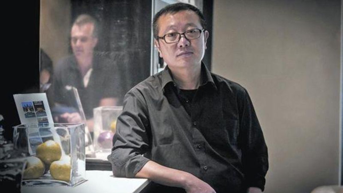 El escritor de ciencia ficción Liu Cixin posa en un céntrico hotel de Barcelona, el lunes. A la derecha, portada de 'El problema de los tres cuerpos' (Nova).-JOAN PUIG