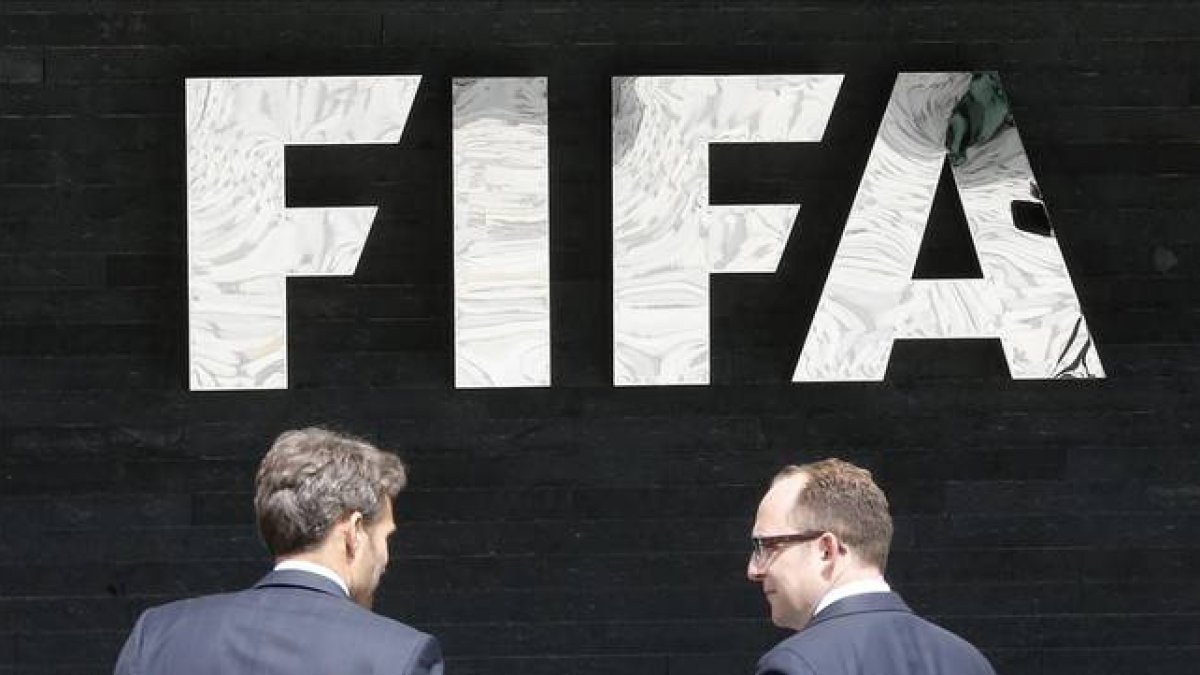 Dos hombres pasan por delante de la sede central de la FIFA en Zúrich.-Foto: AP / MICHAEL PROBST