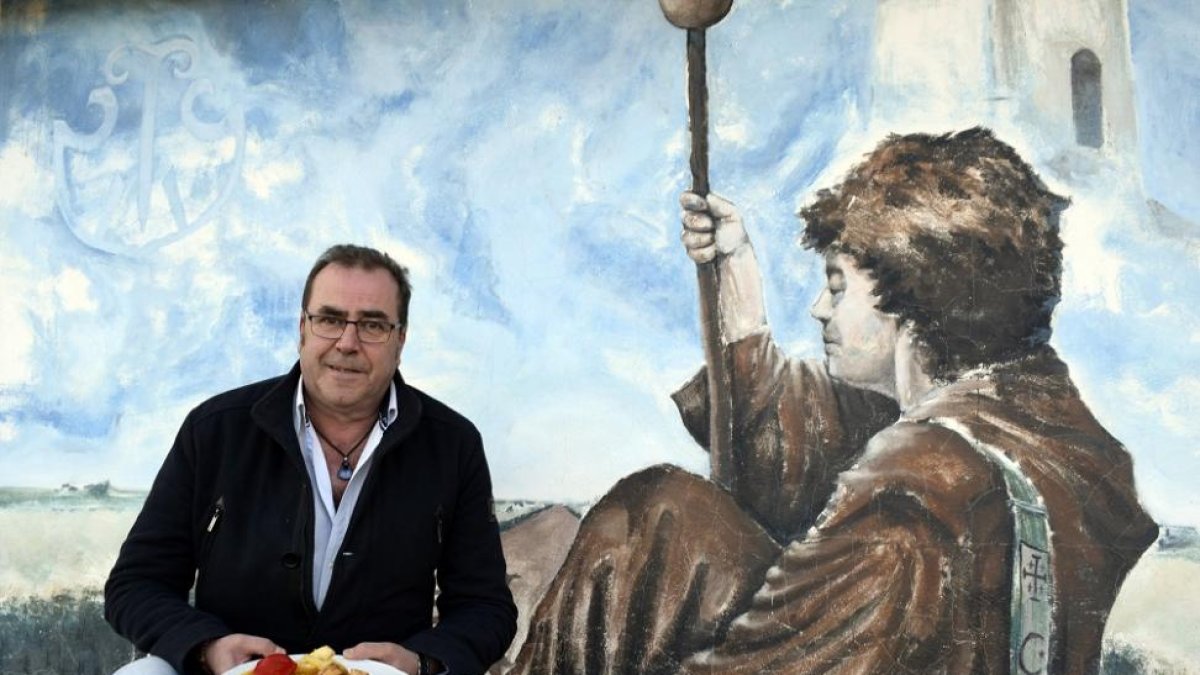 César Acero, con un plato del menú, junto al mural de temática jacobea de su complejo hostelero-ARGICOMUNICACIÓN