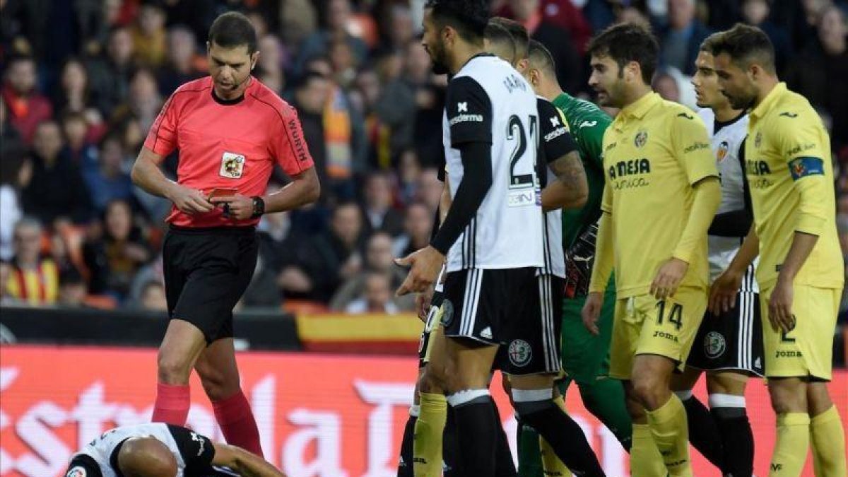 El árbitro del Valencia-Villarreal se dirige a mostrar la segunda amarilla a Zaza, en el suelo.-AFP / JOSÉ JORDÁN