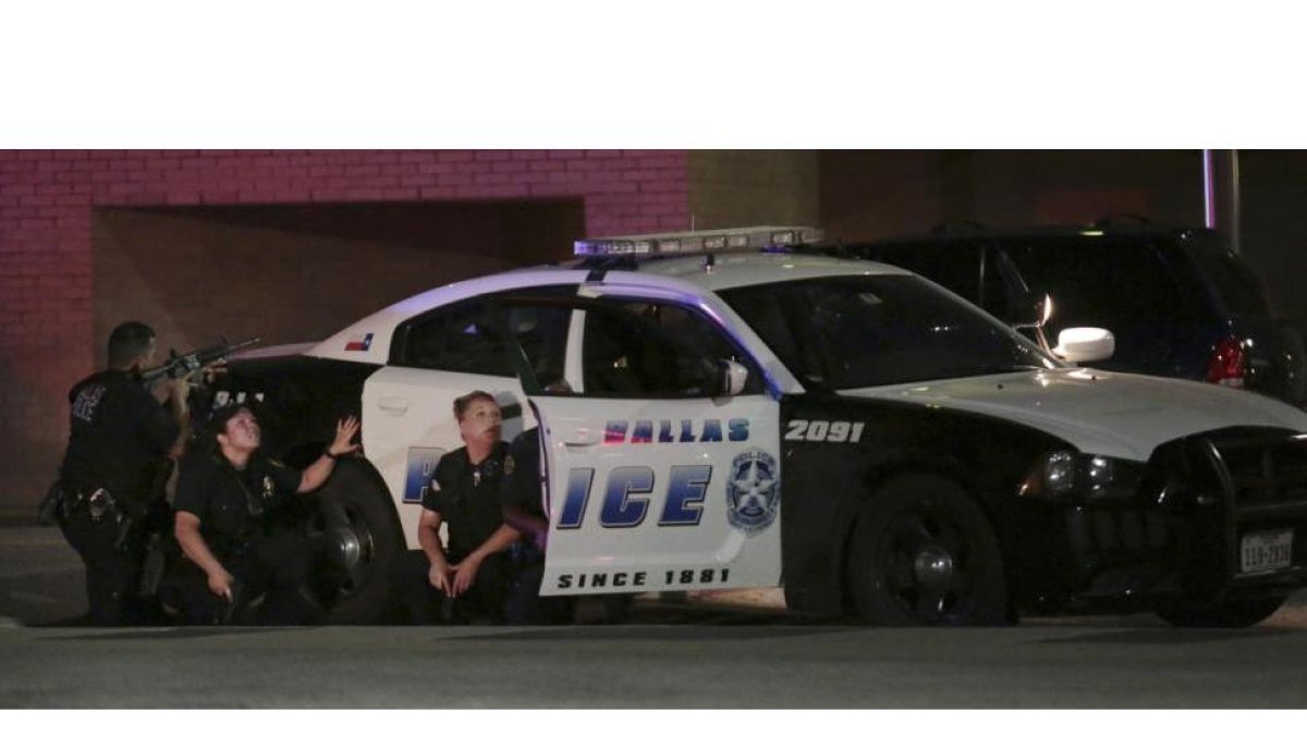 Varios policías, parapetados tras un coche patrulla, durante el tiroteo en Dallas.-Maria R. Olivas / AP
