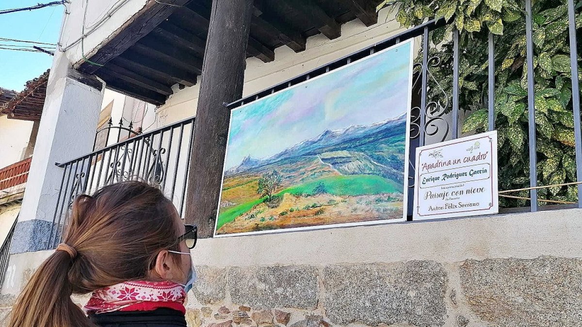 Una turista contempla uno de los cuadros que cuelgan de las calles de una llocalidad. / LA POSADA.
