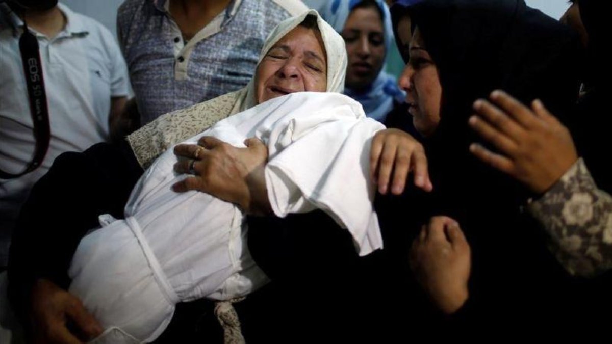 Familiares con el cadáver de la pequeña Laila.-MOHAMMED SALEM