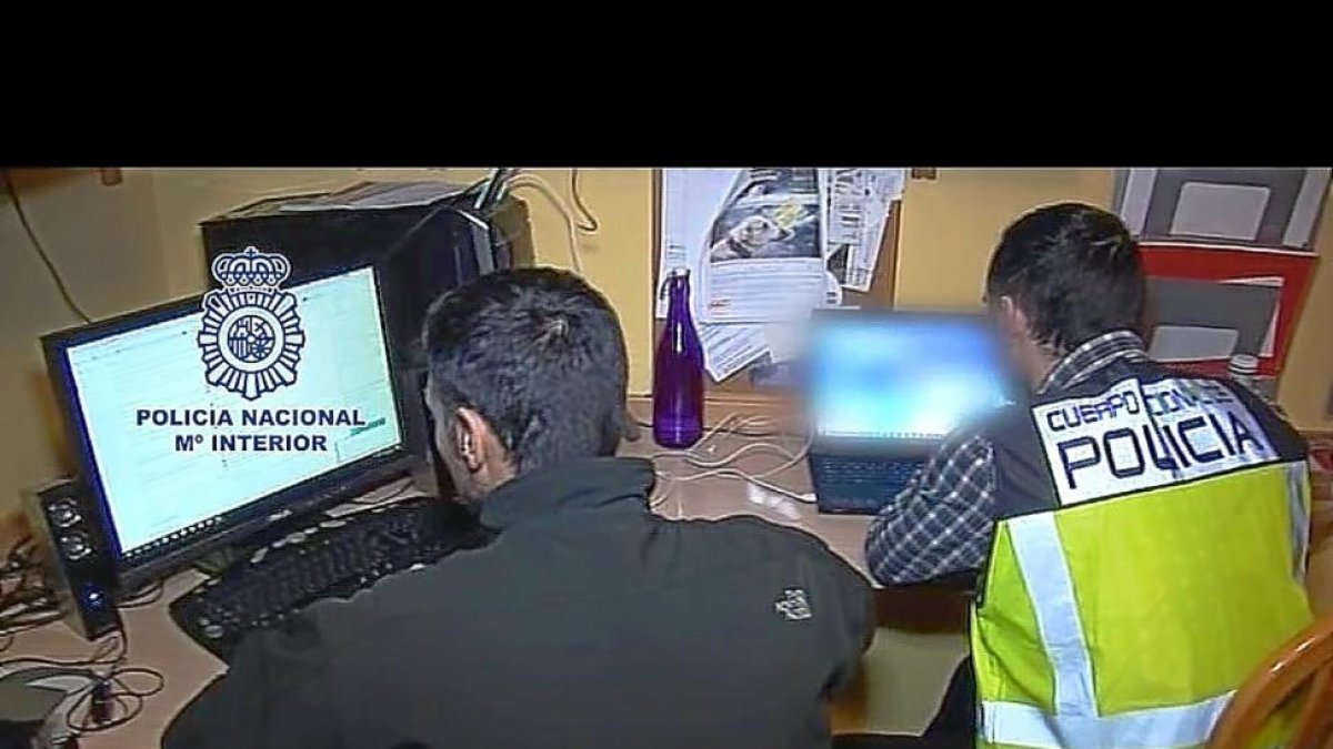 Agentes del Cuerpo Nacional de Policía revisan los ordenadores de uno de los detenidos en España.-E. M.