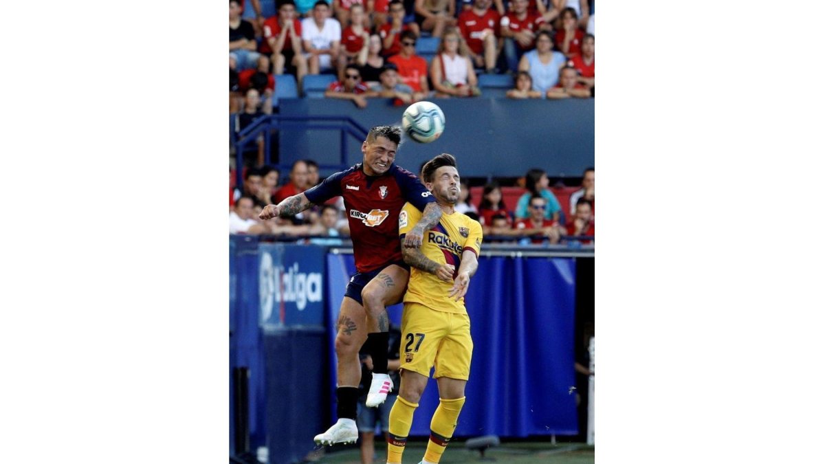 El delantero argentino de Osasuna Chimy Ávila (i) disputa un balón con Carles Pérez, del FC Barcelona, en el partido correspondiente a la 3ª Jornada de LaLiga Santander que Osasuna y FC Barcelona disputan hoy sábado en el estadio El Sadar, en Pamplona.-EFE
