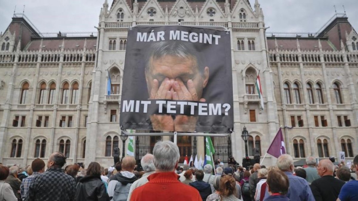 Un hombre sostiene un póster con la imagen de Orbán donde se lee: '¿Qué he hecho otra vez?', en un acto de protesta de partidos opositores al presidente húngaro, en Budapest, este domingo.-AP / VADIM GHIRDA