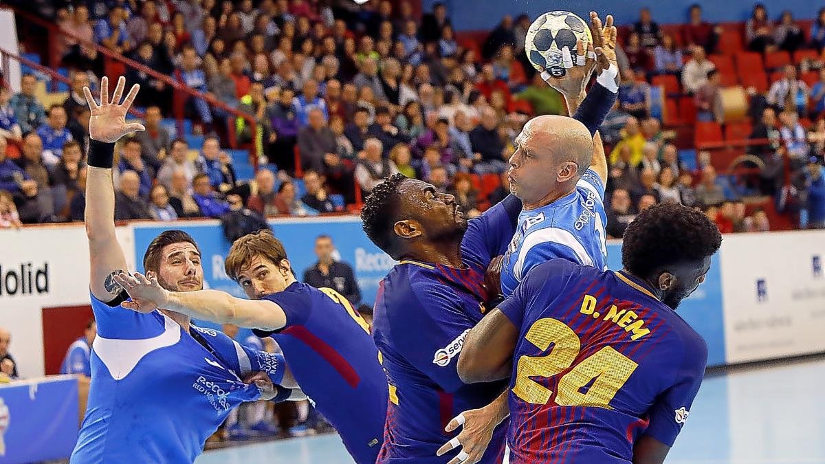 Diego Camino intenta lanzar entre los dos jugadores del Barcelona.-J.M.L.
