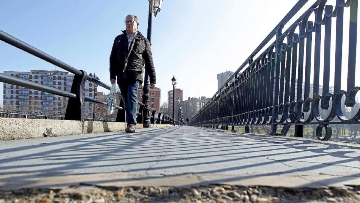 Un peatón camina por una de las aceras del puente Mayor, en la que se aprecia una grieta.-J.M. LOSTAU