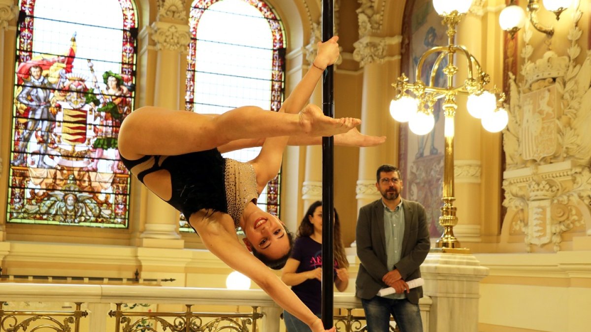 En primer plano, una deportista haciendo un ejercicio de pole dance en el Ayuntamiento de Valladolid tras la presentación del Campeonato de Europa. / EM