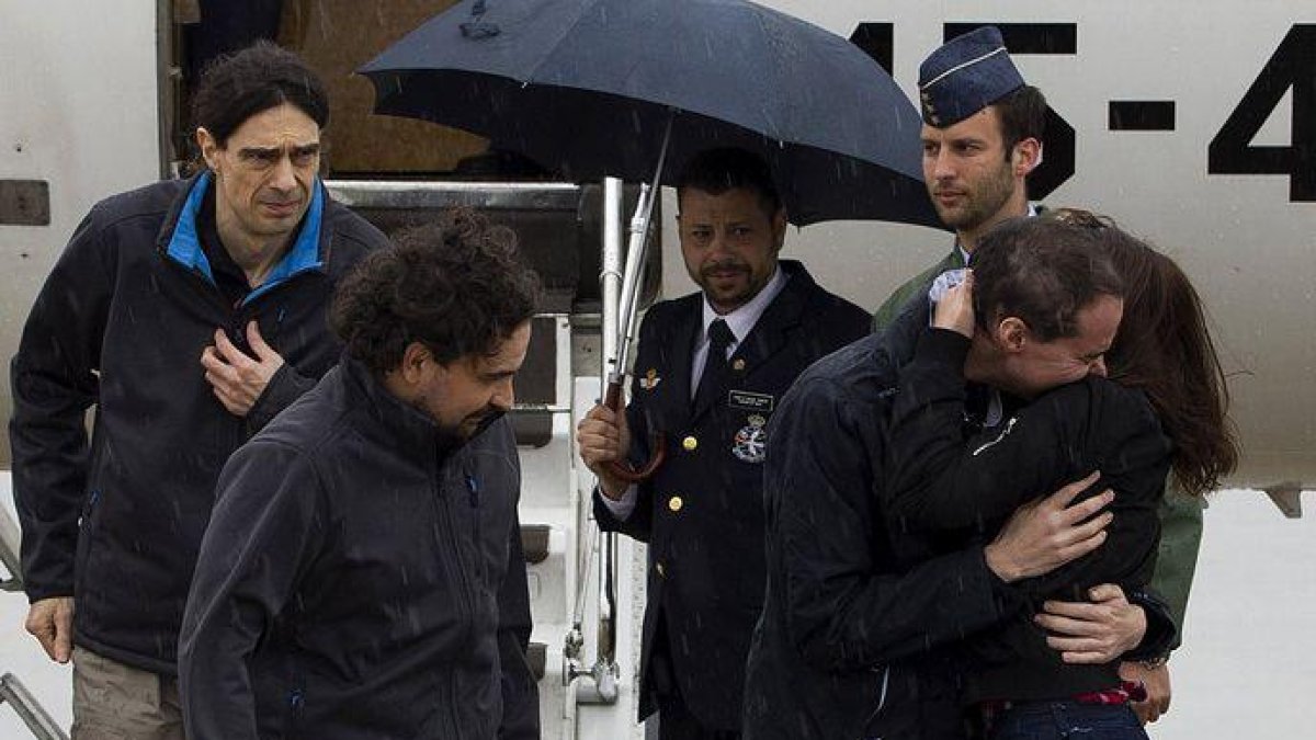 Ángel Satre, en el centro, José Manuel López, a la izquierda, y Antonio Pampliega, a la derecha, abrazado a un familiar.-EFE/ DIEGO CRESPO