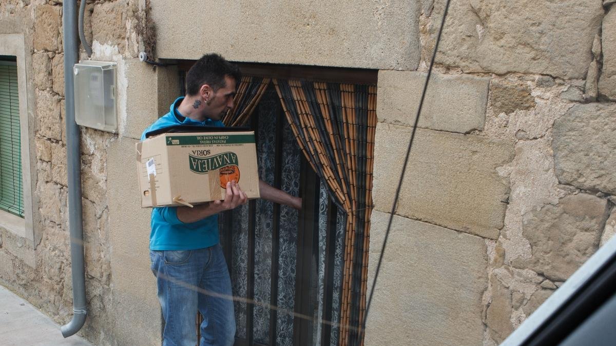 Un empleado lleva la compra a domicilio a una vivienda de un pueblo.-ICAL