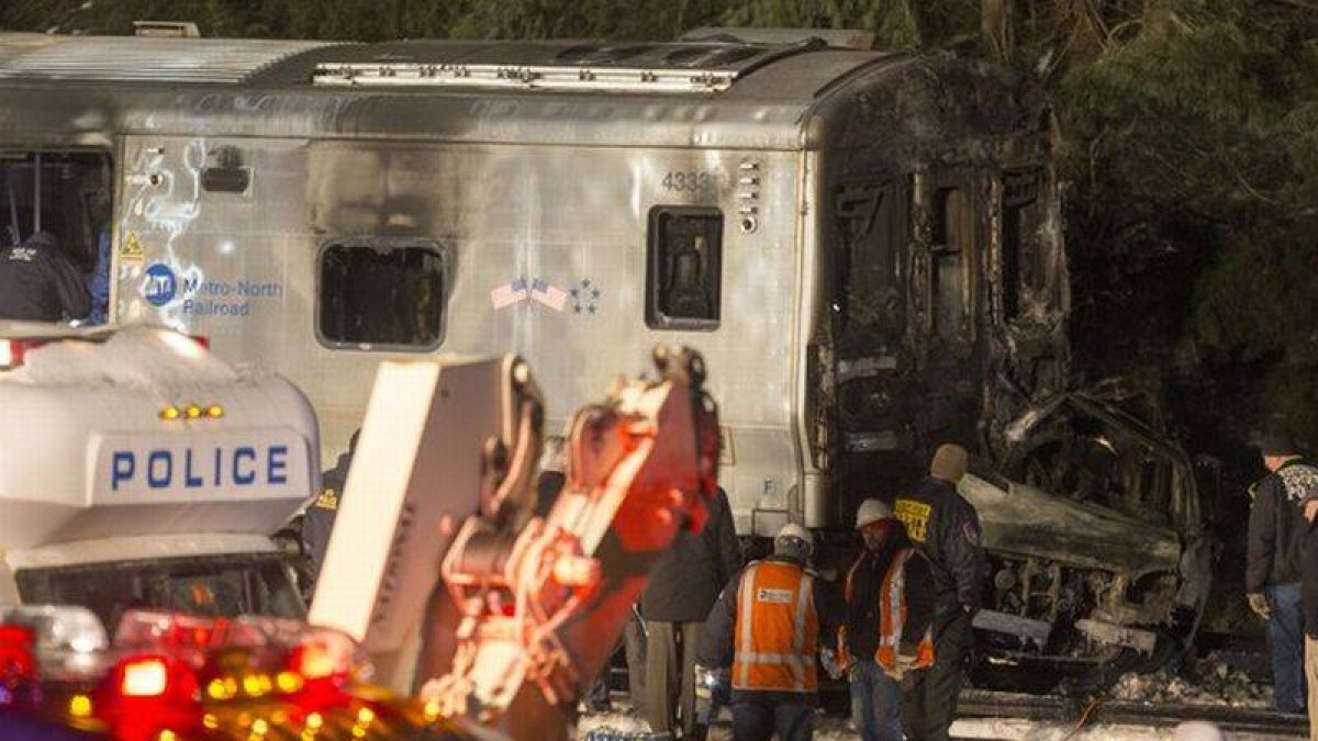 Los servicios de emergencias, ante la locomotora del tren y el vehículo, totalmente calcinado, en Valhalla (Nueva York).-Foto: AFP / MICHAEL GRAAE