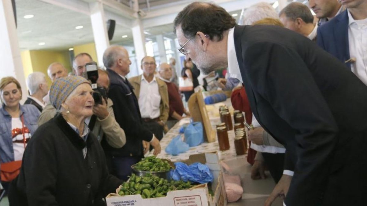 El líder del PP, Mariano Rajoy, charla con una dependienta durante un paseo electoral por Galicia.-EFE/Lavandeira jr
