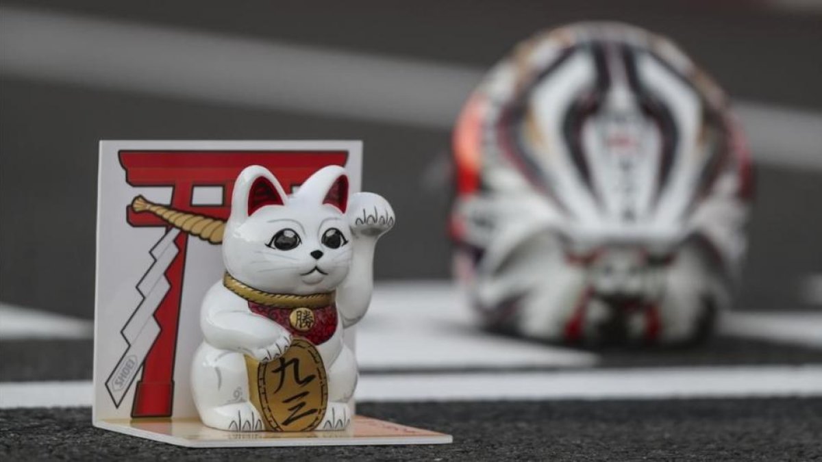 El gato que atrae a la suerte, junto al casco de Marc Márquez, en el box de Motegi en 2016.-ALEJANDRO CERESUELA