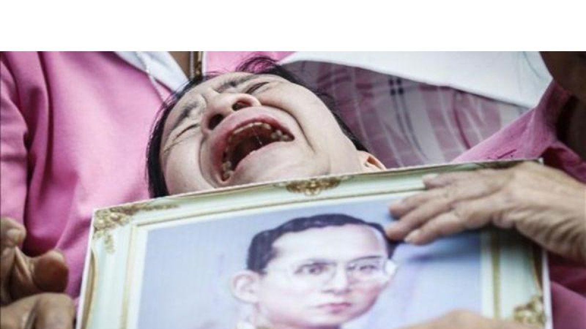 Una mujer llora a las puertas del hospital con la la foto del rey Bhumibol.-EFE / DIEGO AZUBEL