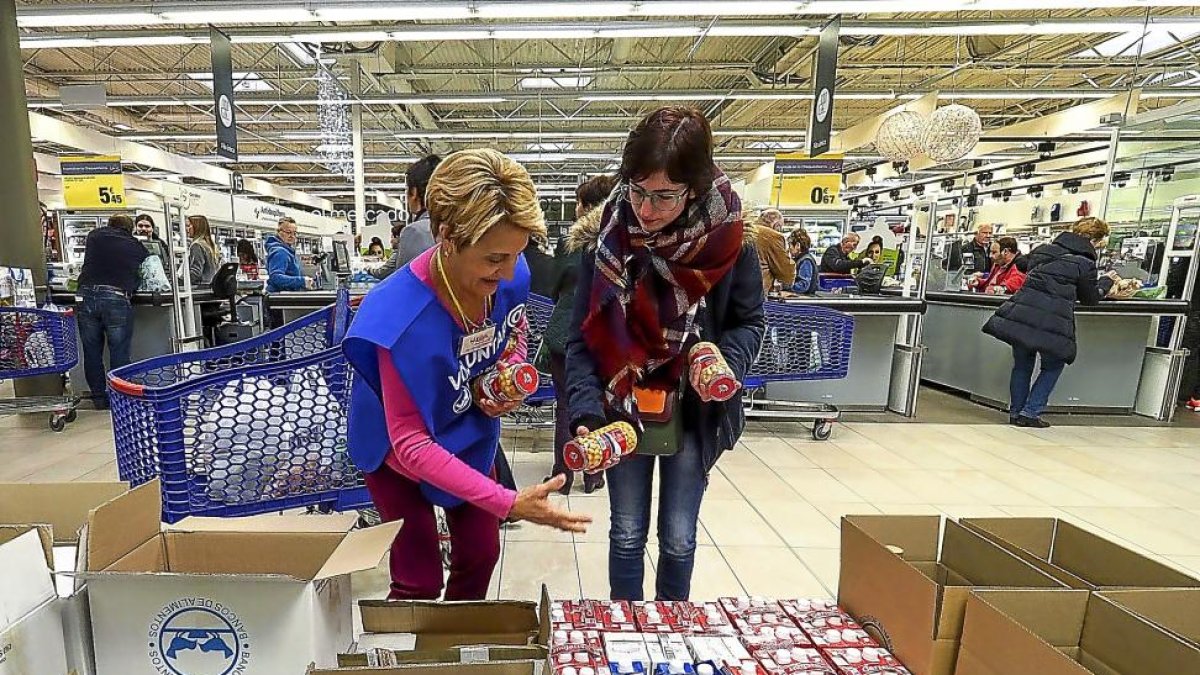 Una mujer le da a una de las voluntarias un bote de garbanzos.-MIGUEL ÁNGEL SANTOS