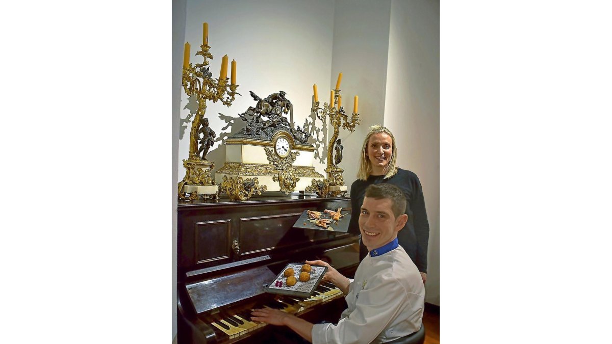 Ángel y Laura, hoy al frente del Duque, junto al piano que decora el comedor del restaurante, y algunos platos representativos de la carta.-ARGI