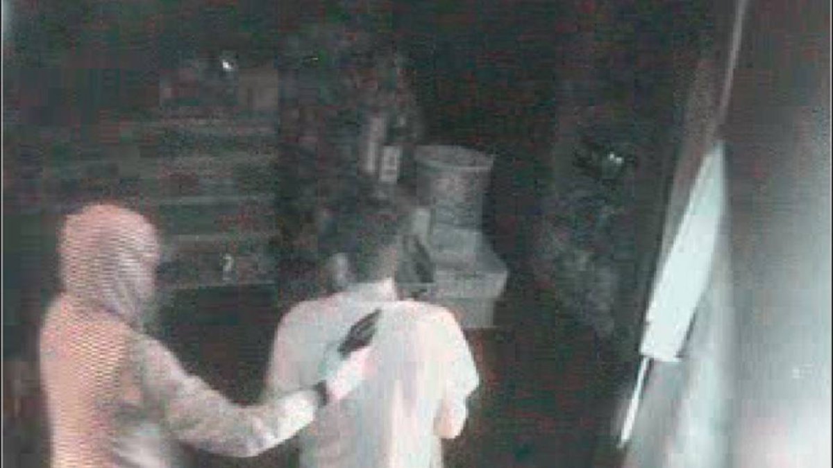 Momento en el que el atracador, con capucha, apunta con el revólver al trabajador nada más entrar en la tienda.-