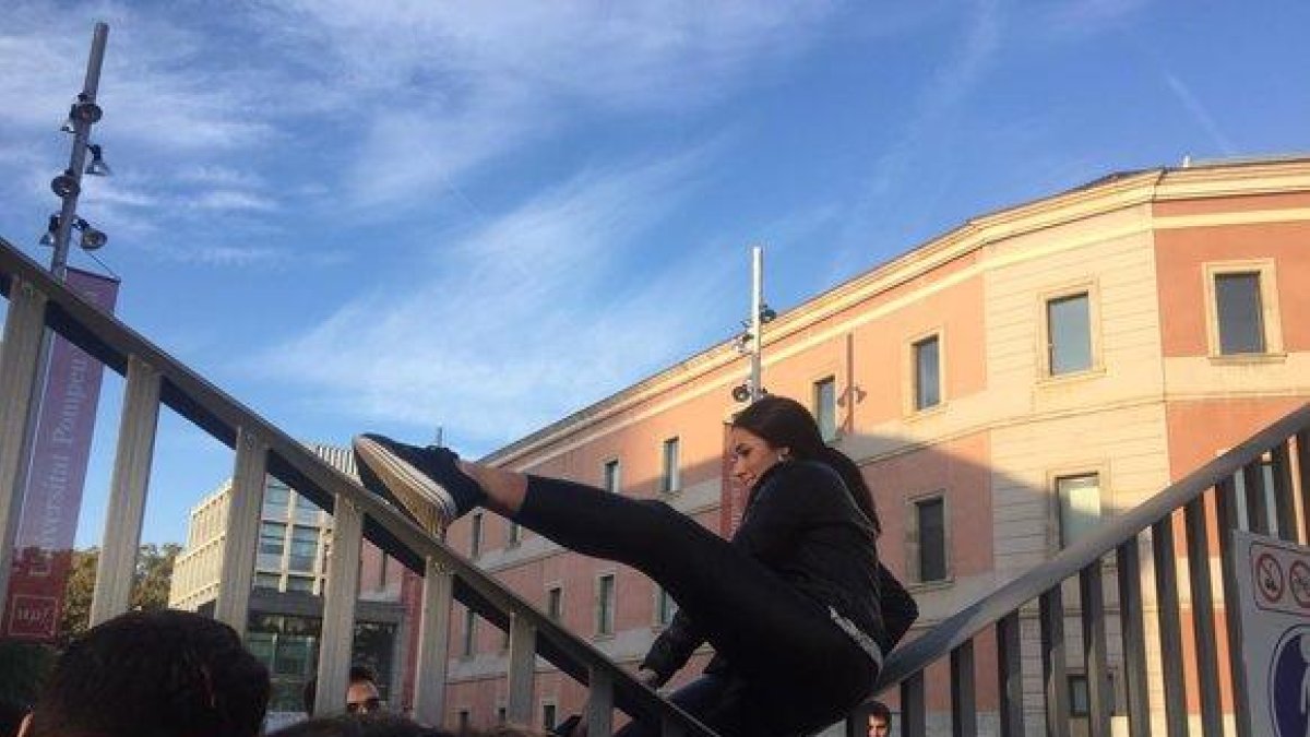 Una estudiante de la UPF, salta la valla para ir a clase, esquivando el piquete de huelga.-GEMMA TRAMULLAS
